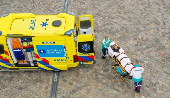 Ambulancepersoneel plaatst een persoon op een brancard in de ambulance